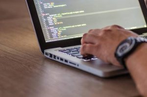 man writing code on laptop